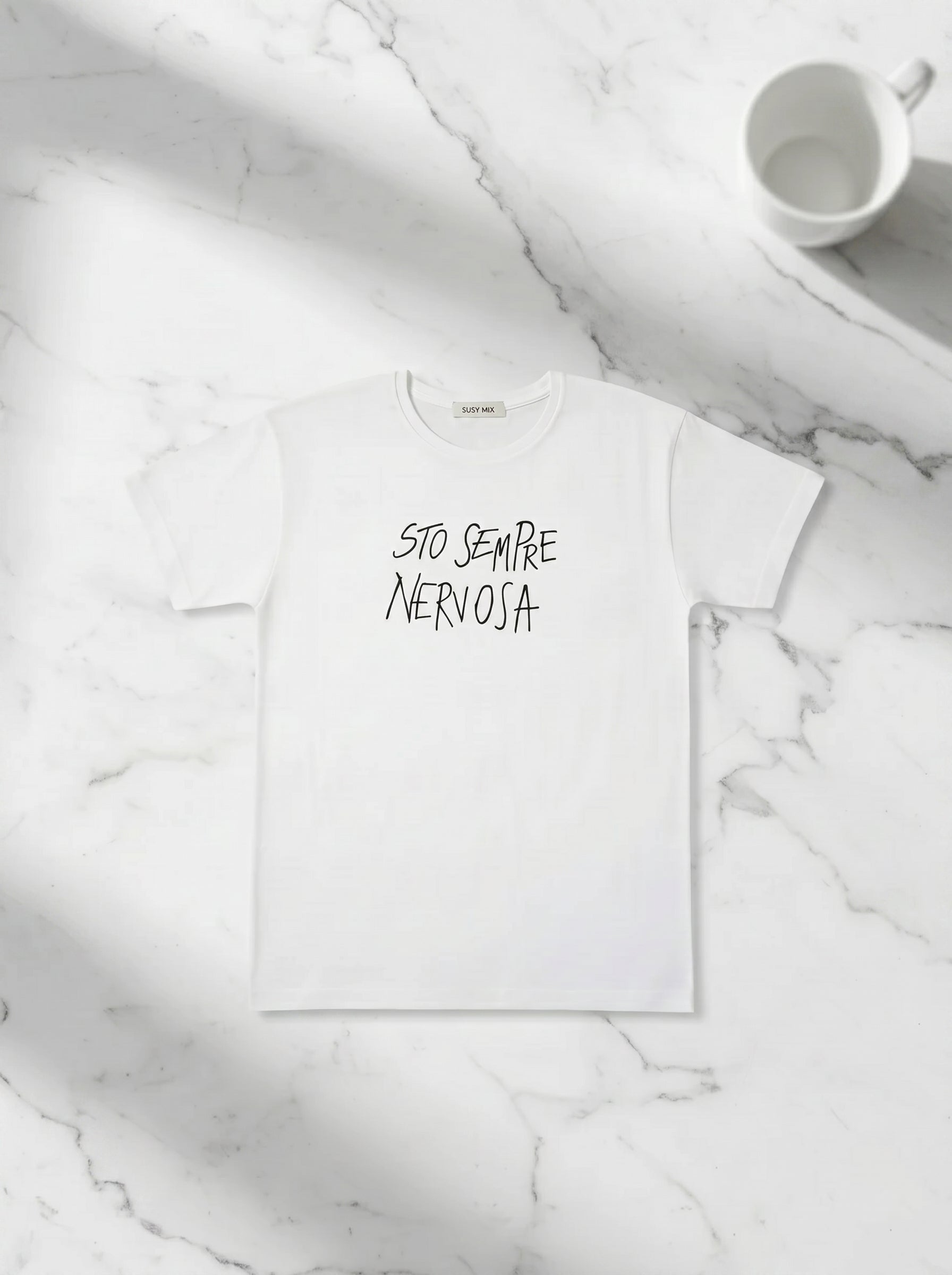 Balti marškinėliai „Sempre Nervosa“ Susy Mix ant stalo